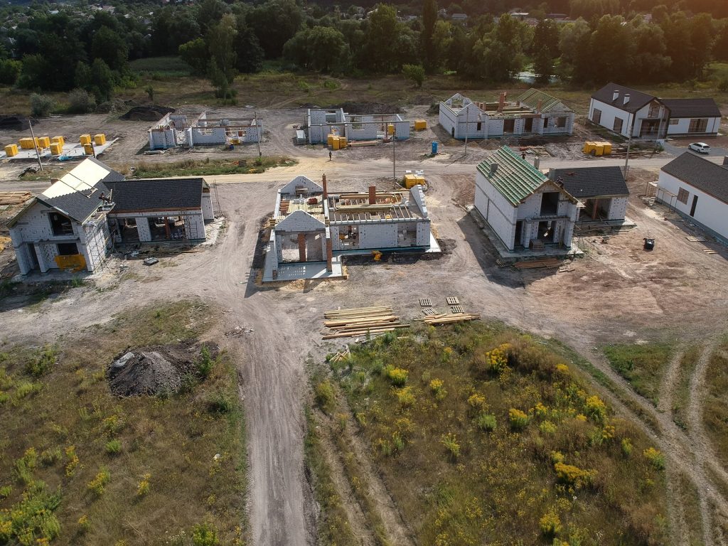 Aerial view of a new residential construction site with multiple houses in progress. TITLE: