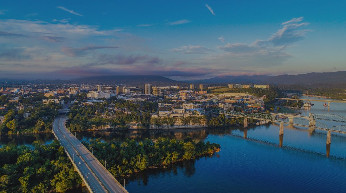 An aerial view reveals a vibrant city skyline along a wide river with multiple bridges and distant