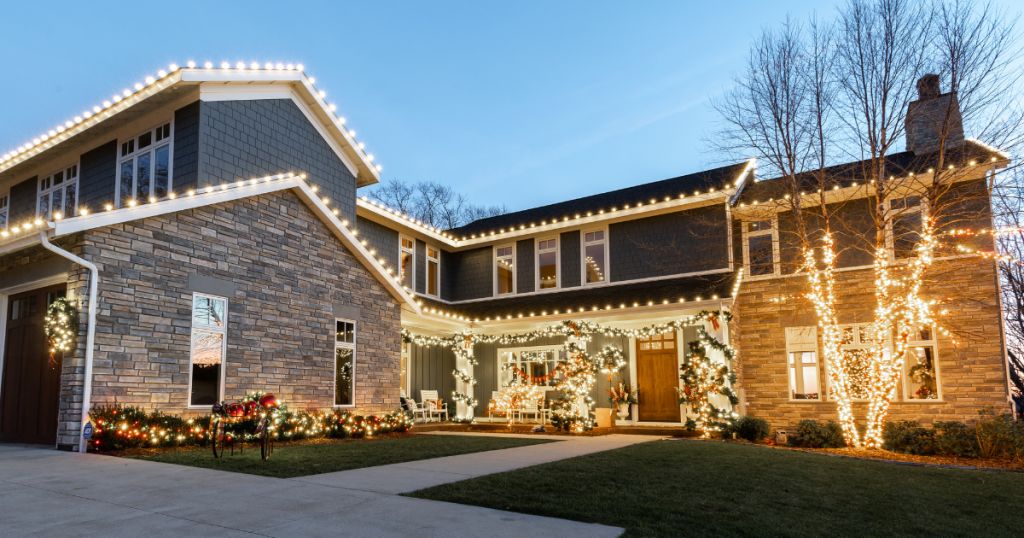 Modern home illuminated with festive warm white Christmas lights and garlands at twilight.