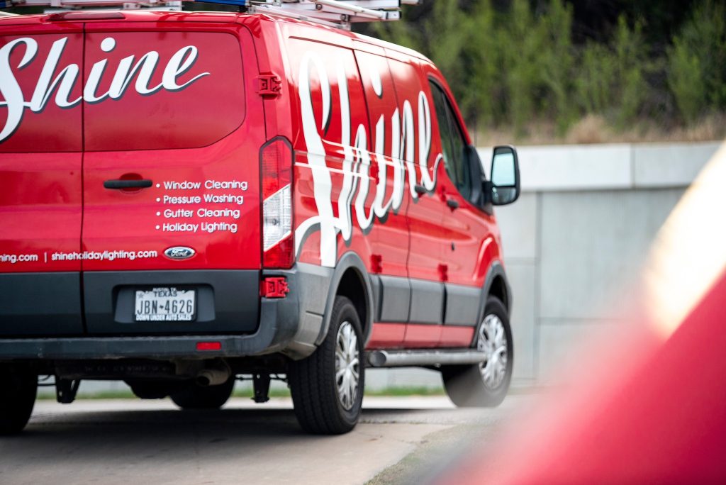 Red Shine service van displaying window cleaning, pressure washing, gutter cleaning, and holiday lighting services