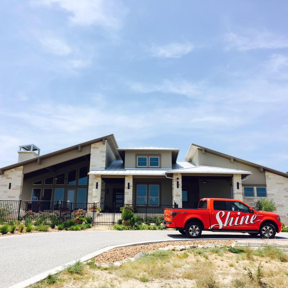 A contemporary home with stone accents and an orange "Shine" service truck parked