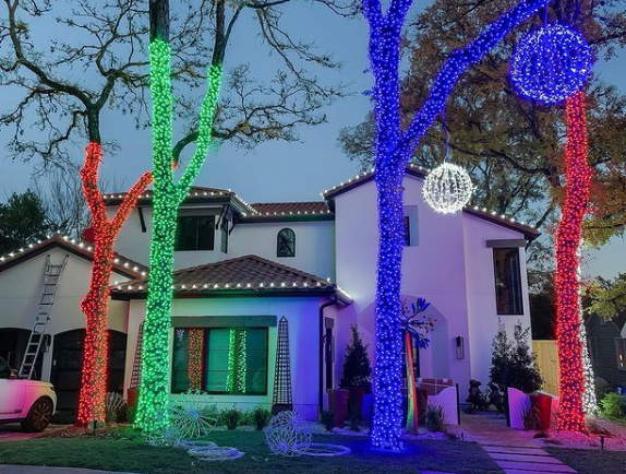 Home holiday lighting on roof edges plus trees wrapped in various colors