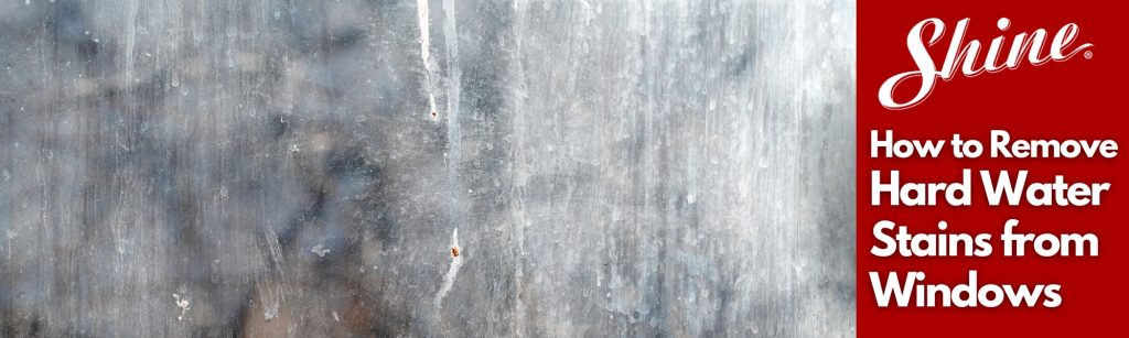 A dirty window pane covered in visible hard water stains and streaks.