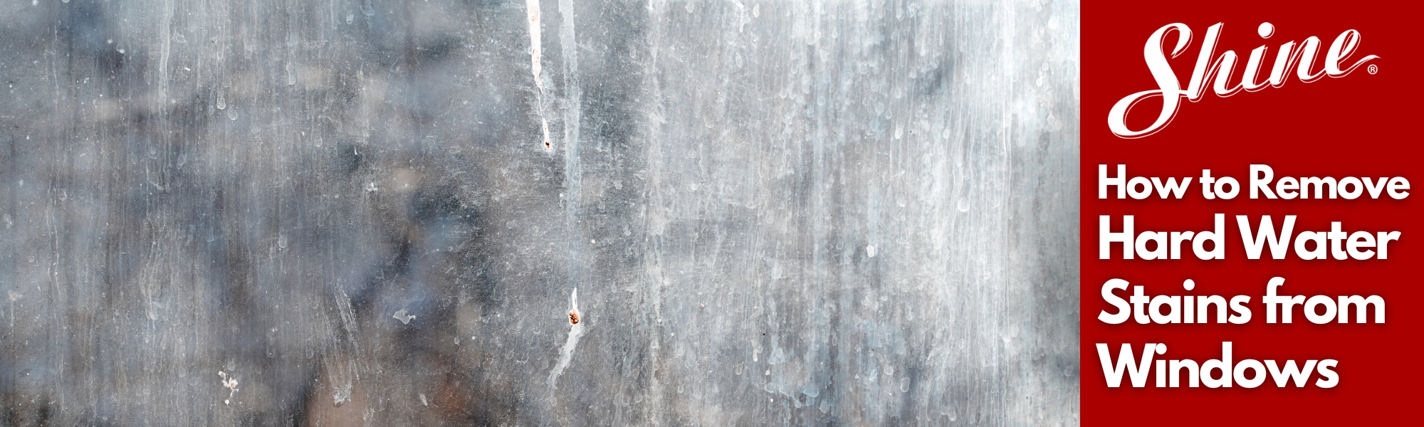 A dirty window pane covered in visible hard water stains and streaks.