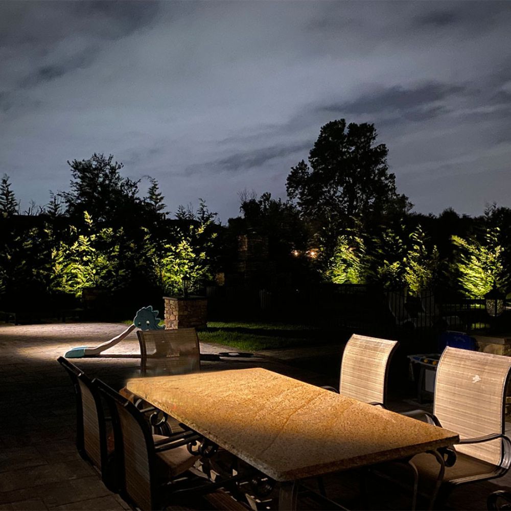 Landscape lighting with perimeter up-lighting, spot lights for art, and an an outdoor dining area.
