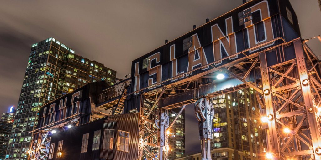 The iconic illuminated "LONG ISLAND" sign stands prominently at night, framed by glowing