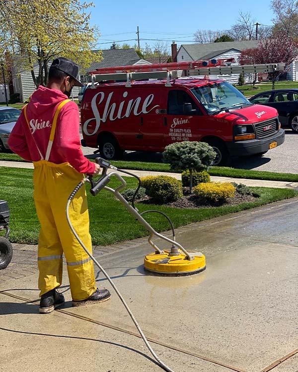 Driveway cleaning, power washing on dirty driveway. Maintenance by Shine with branded van