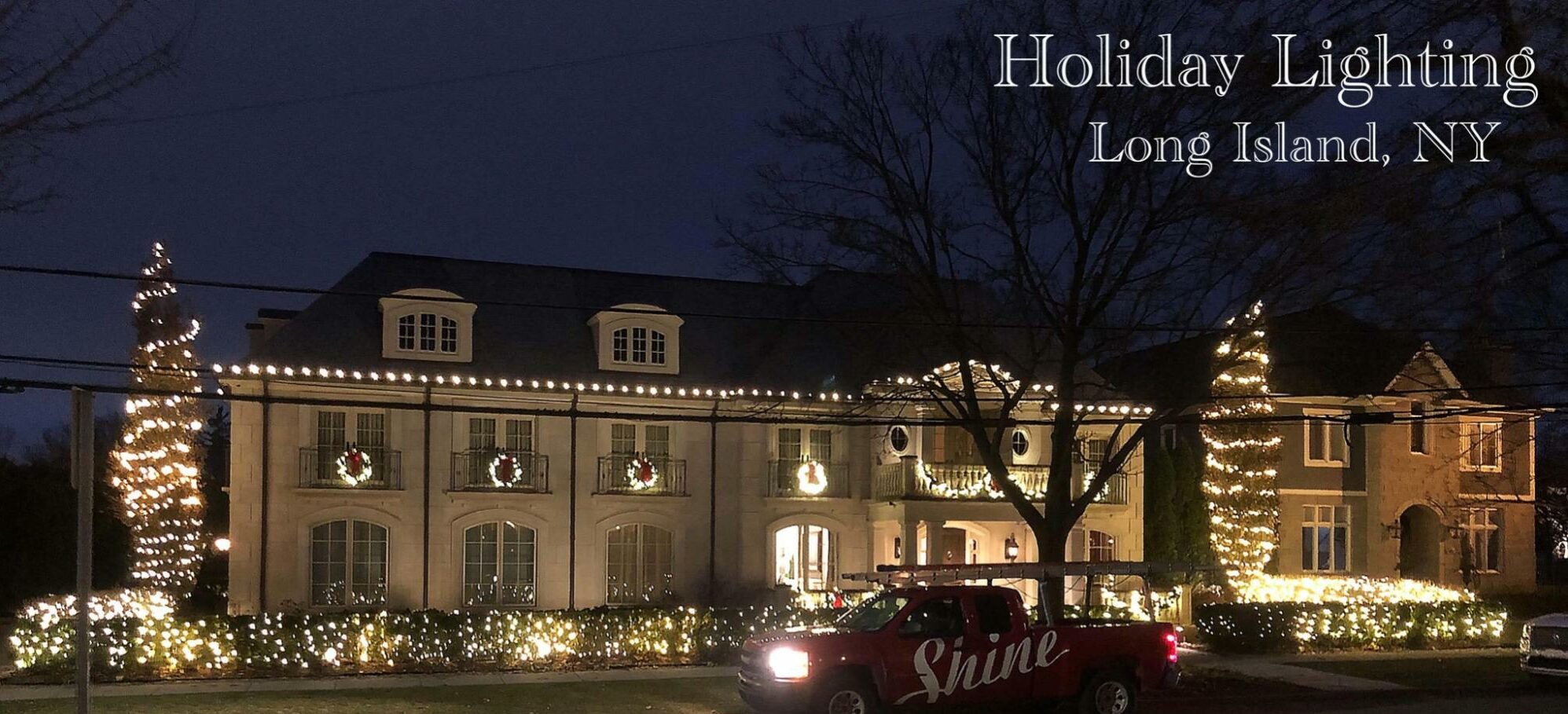 A large Long Island house is brightly lit with holiday lights, featuring a "Shine