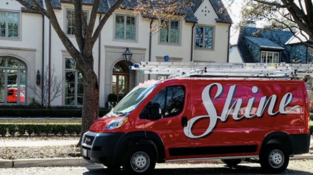 Red Shine service van with ladders parked on a street in front of a stately home.