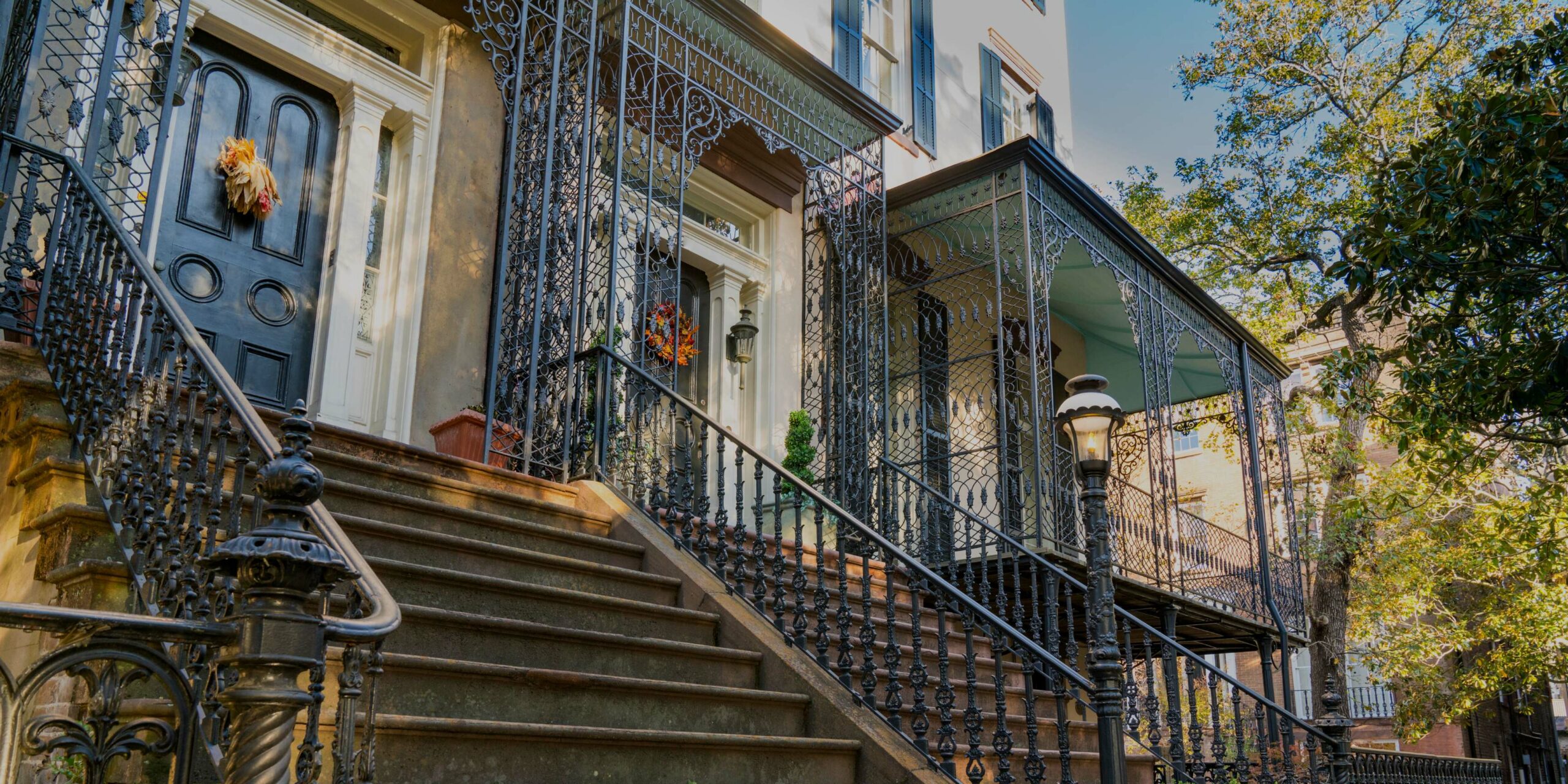 Elegant historic townhouses feature ornate black wrought iron railings, grand stone steps, and decorative doors.