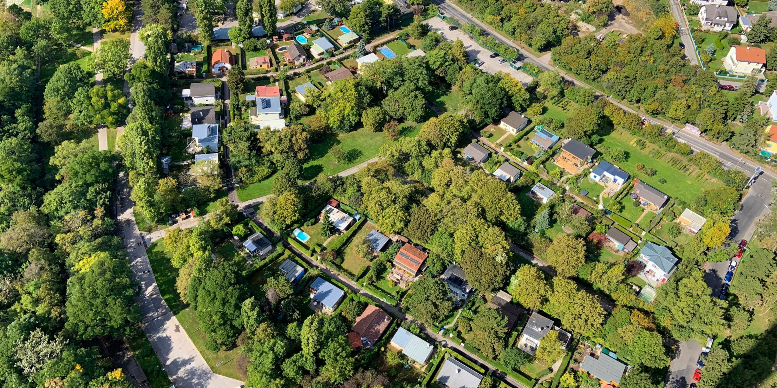 Aerial view of a lush green residential neighborhood with many houses, trees, and roads