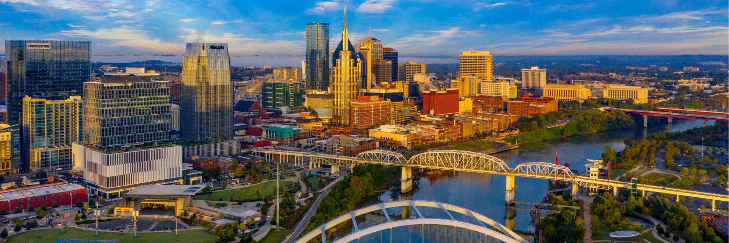 An aerial panorama of Nashville's vibrant skyline, featuring the Cumberland River, bridges, and numerous