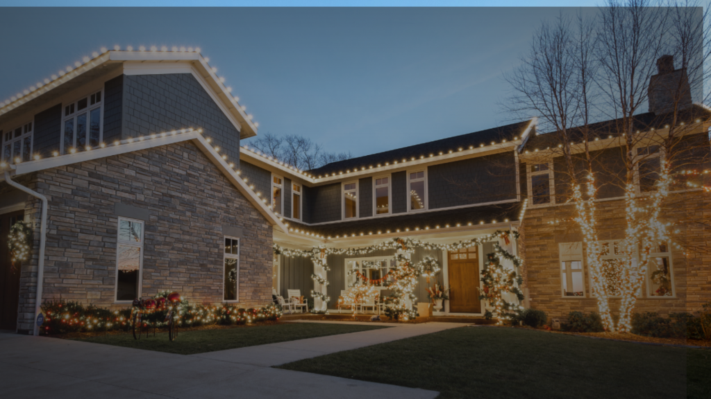 Elegant home adorned with glowing warm white holiday lights on its roof, porch, and