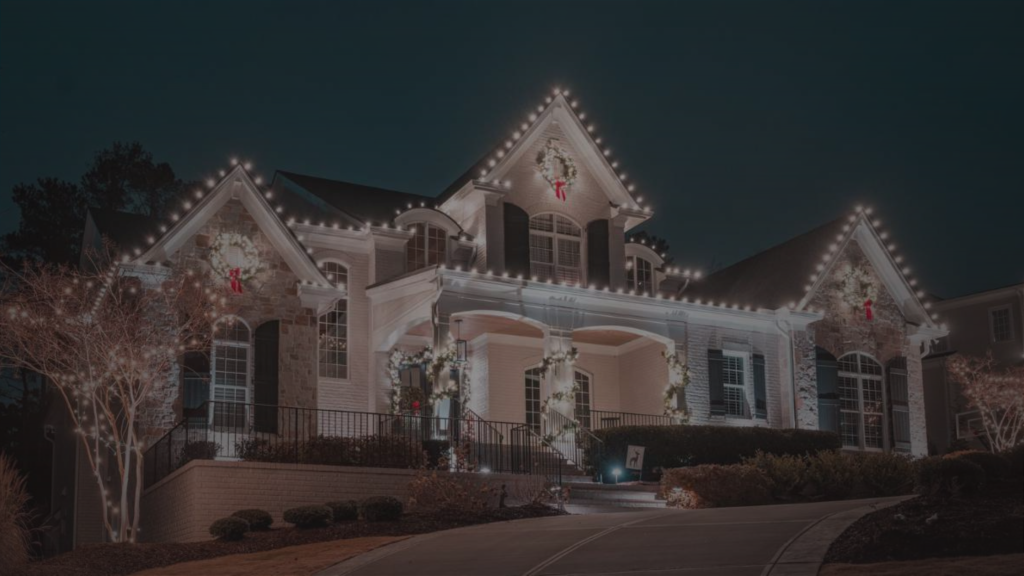 A large house is beautifully decorated with bright Christmas lights and wreaths at night.