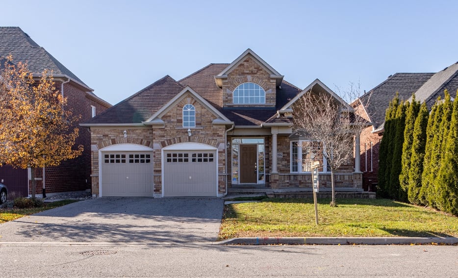 Modern stone and brick house with a double garage under a clear blue sky.