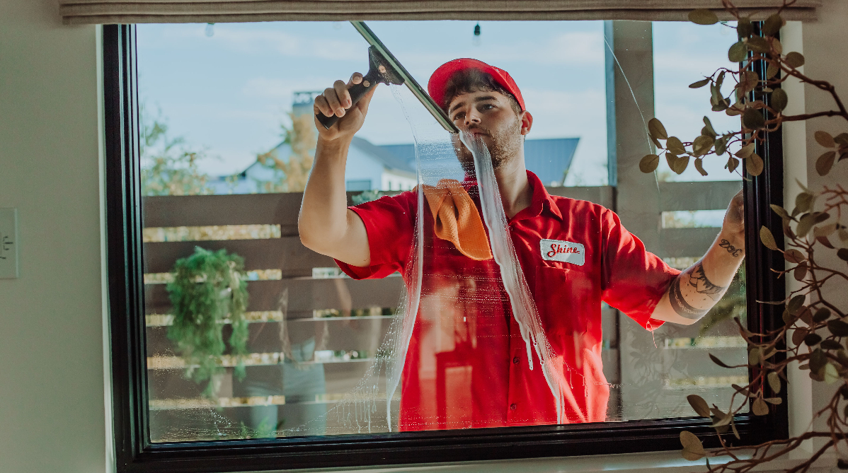 A man in a red uniform with a 'Shine' name tag cleans a