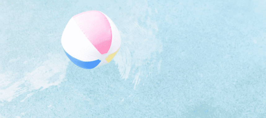 A pink, white, and blue beach ball floats on a light blue water surface.