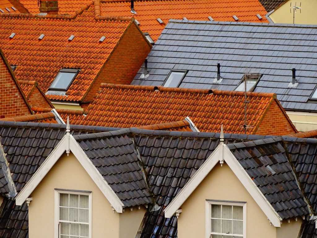 A dense cluster of orange and grey tiled rooftops with multiple dormer windows and skyl