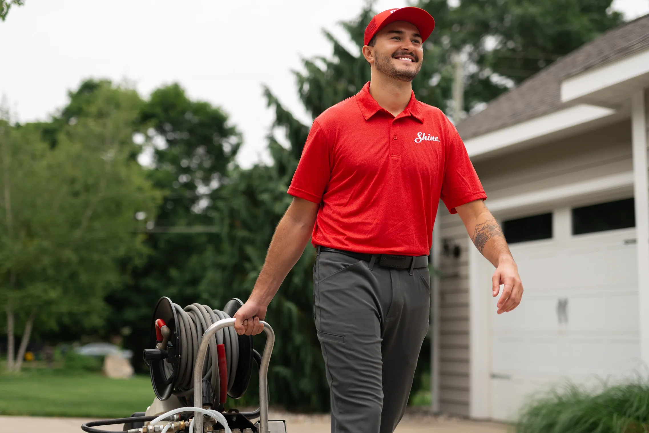 Shine technician smiling while pulling a hose cart in front of a home