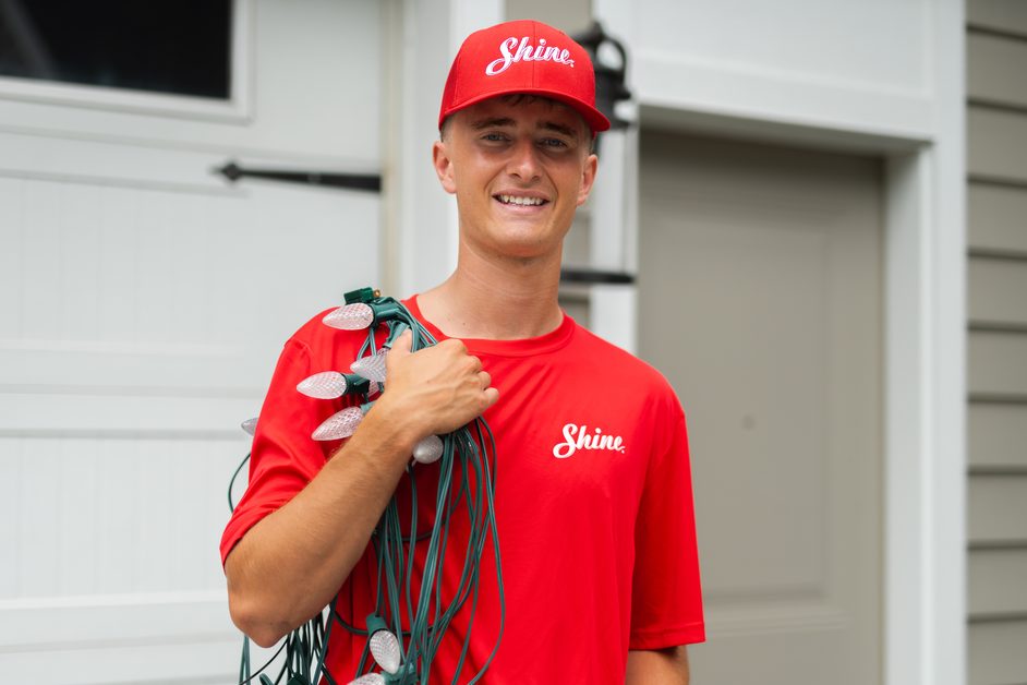 Shine technician carrying a coil of outdoor lighting