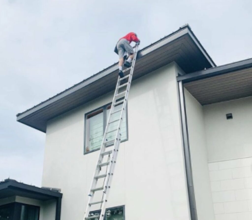 A Shine worker climbing to the roof of a client’s home for some exterior cleaning.