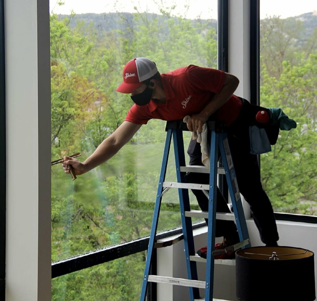 Shine employee cleaning windows