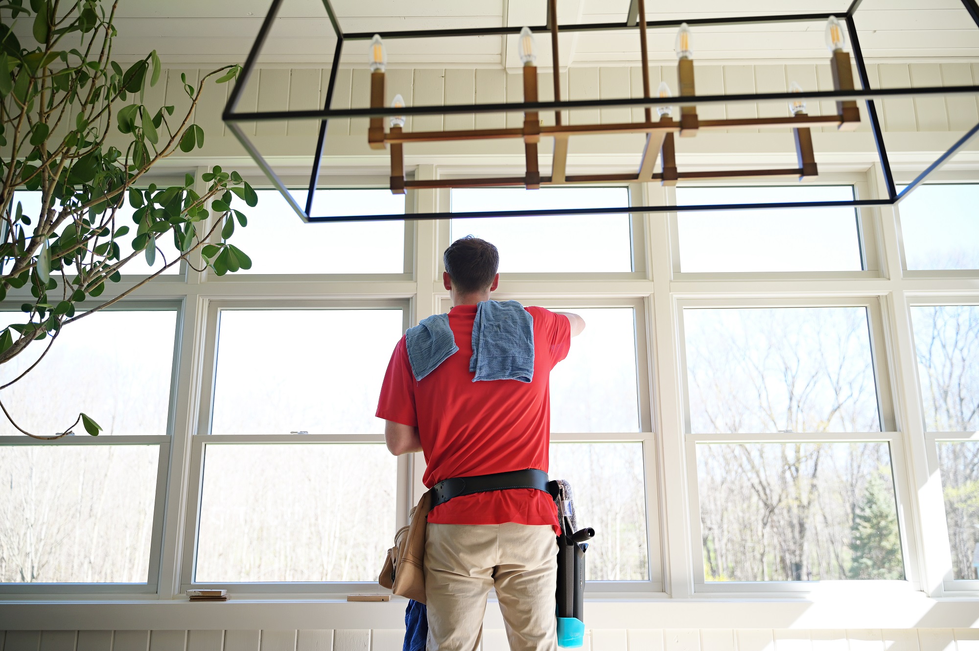 Shine technician using a water-fed pole to clean a second-story window