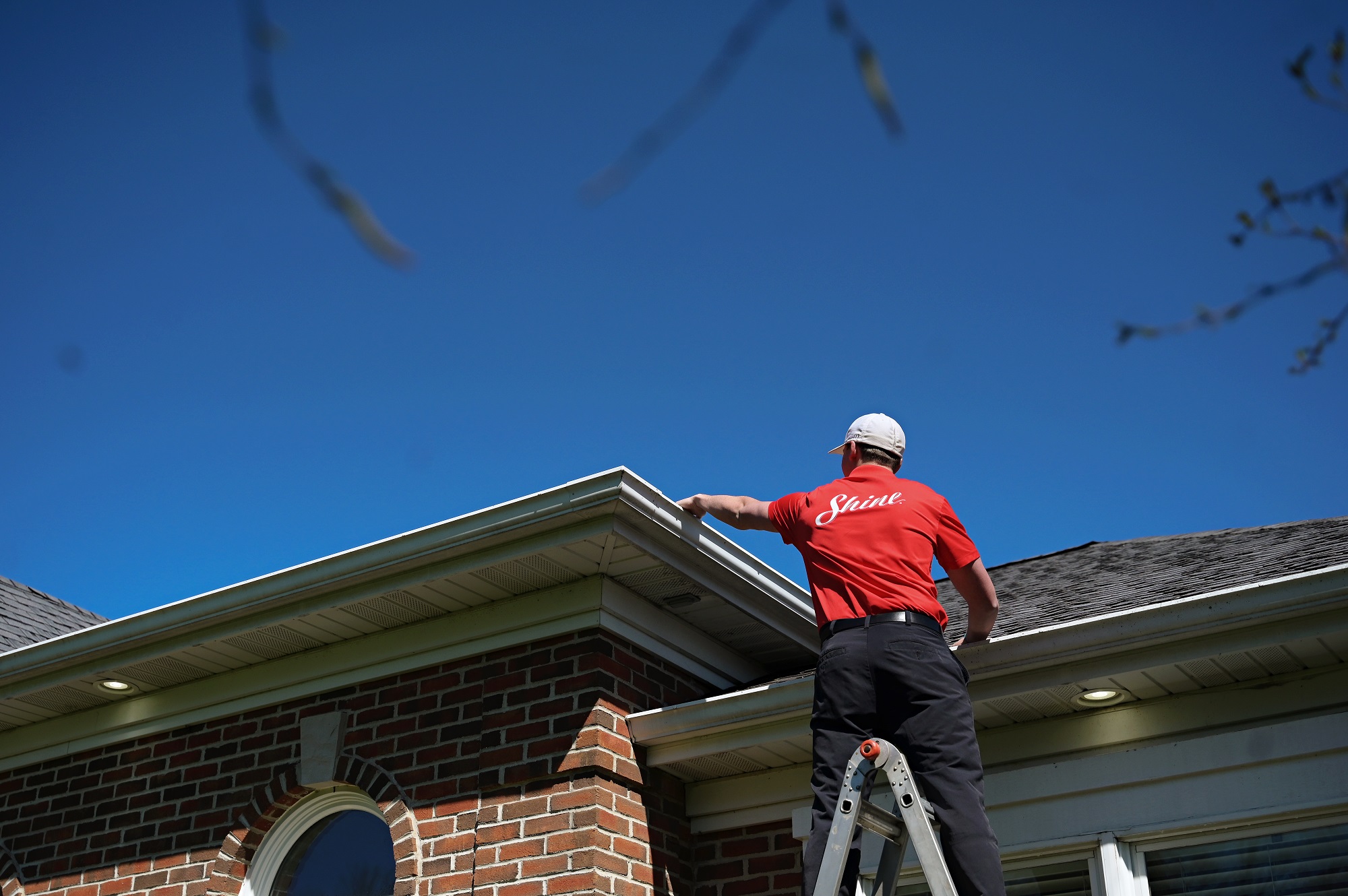 Shine technician using a water-fed pole to clean a second-story window