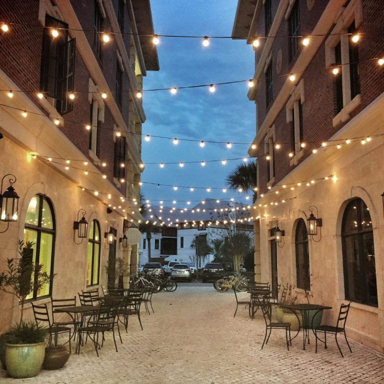 Large home decorated with warm white Christmas lights along the roofline, windows, and front entrance.