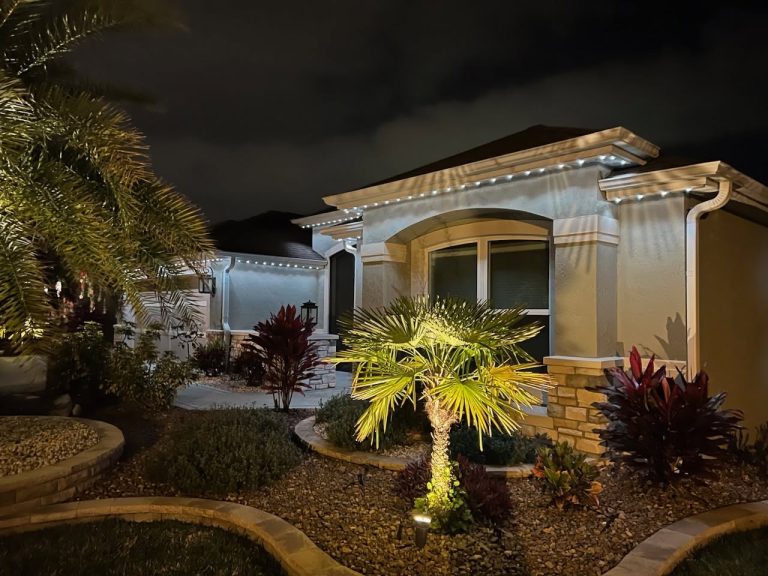 Home exterior illuminated at night with landscape and architectural lighting.