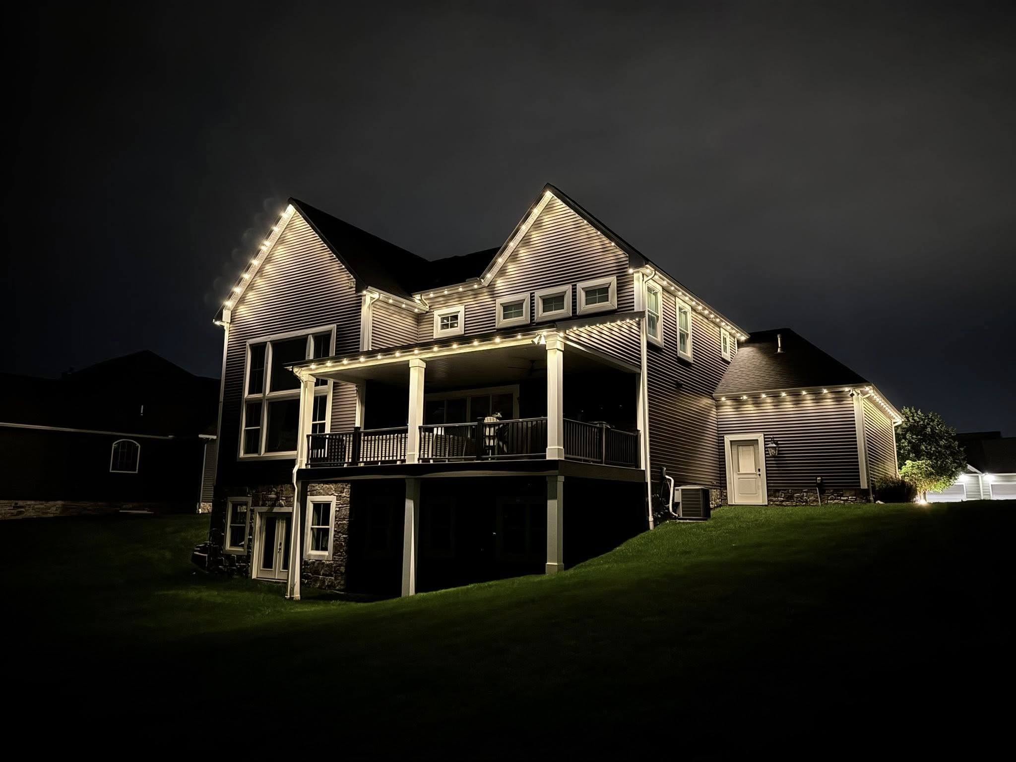 Home with permanent architectural outdoor lighting at dusk