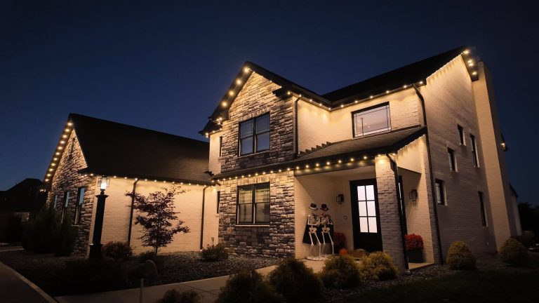 Two-story home illuminated at night with warm exterior architectural lighting.
