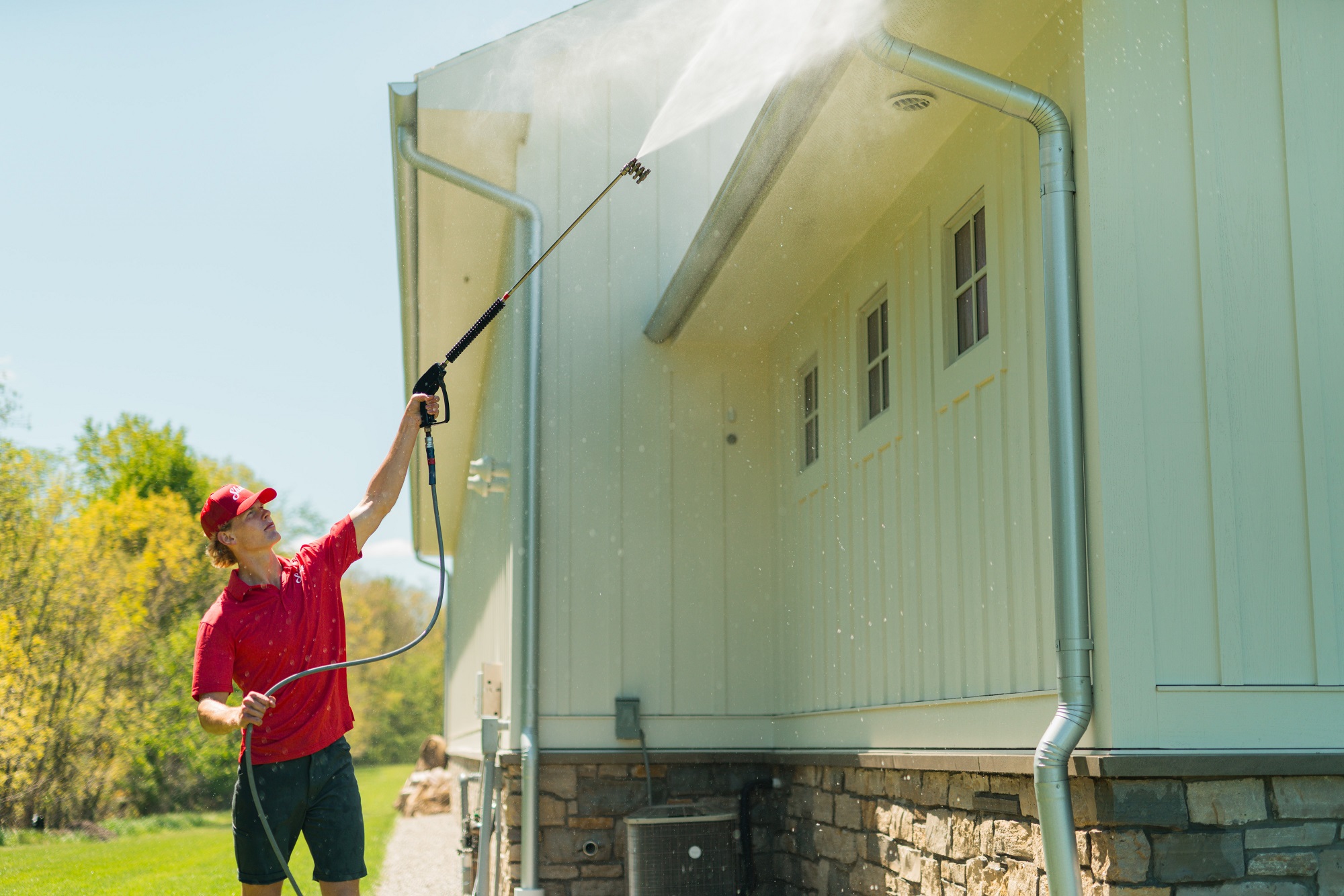 Shine technician using a water-fed pole to clean a second-story window