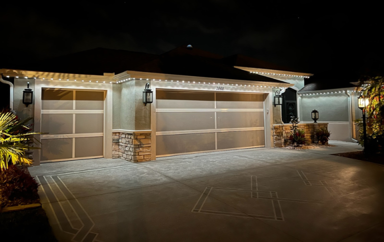 Florida home with white permanent lighting on the exterior of the roofline showing light on driveway and garage