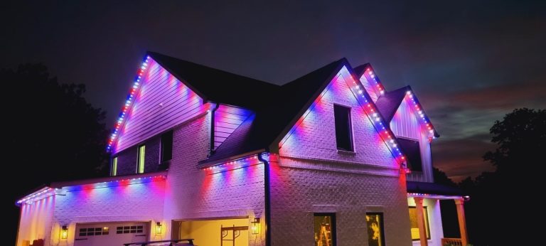 Two-story home illuminated at night with multicolor permanent roofline lighting.