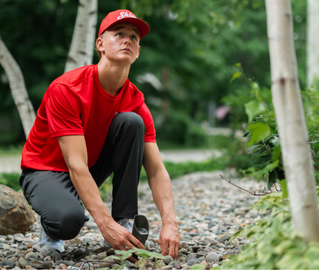 Shine technician in a red uniform holding lighting in a garden