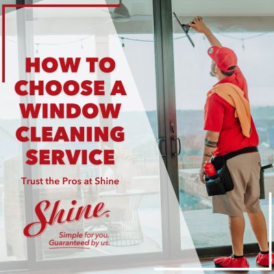 A professional window cleaner cleans a large glass window with a squeegee, promoting a