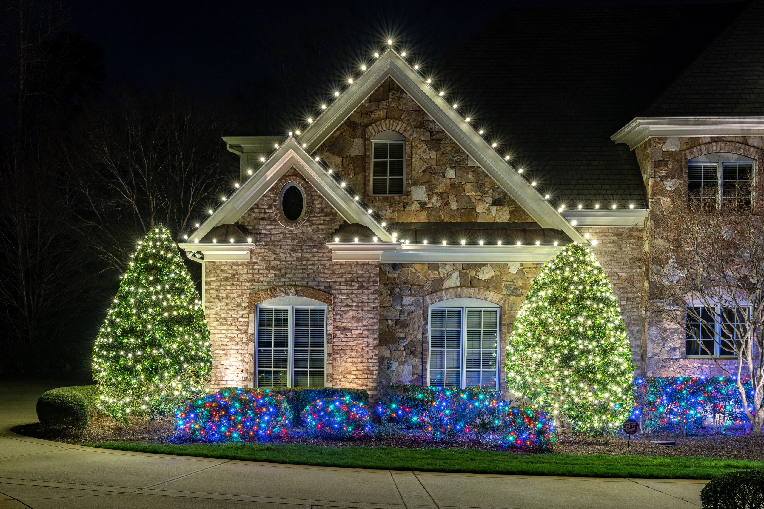 Shine technician in a red shirt carrying holiday lights beside a ladder